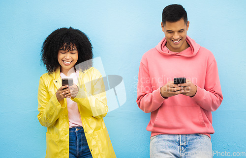 Image of Happy couple, bonding and phone typing on isolated blue background on social media, dating app or travel networking. Smile, man or black woman on mobile technology or community communication website