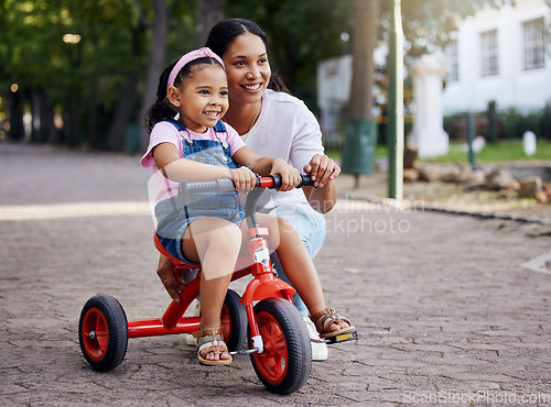 Image of Mother, little girl and bicycle teaching with training wheels for learning or practice at the park. Happy mom helping child to ride her first bike with smile for proud playful moments in the outdoors