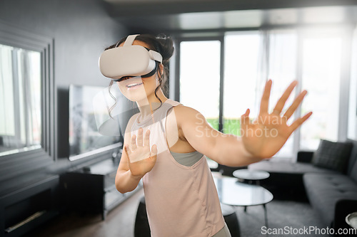 Image of VR, metaverse and futuristic with a woman in the living room of her home using a headset to access a 3d game. Technology, virtual reality and gaming with a female gamer using ai to play online games