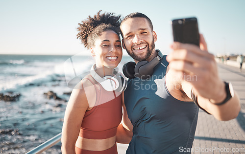 Image of Fitness, couple and phone with smile for selfie, running exercise or workout in the outdoors. Happy man and woman smiling in happiness looking at smartphone for photo after run by the ocean coast