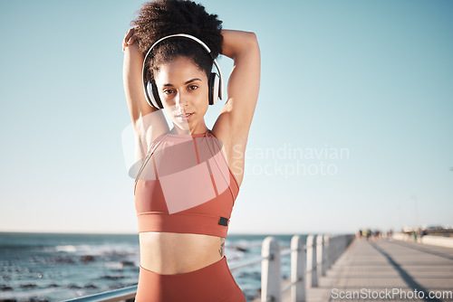 Image of Beach, stretching and portrait of a woman athlete doing exercise before running or training for a race or marathon. Fitness, sports and female runner doing arm warm up before cardio workout by ocean.