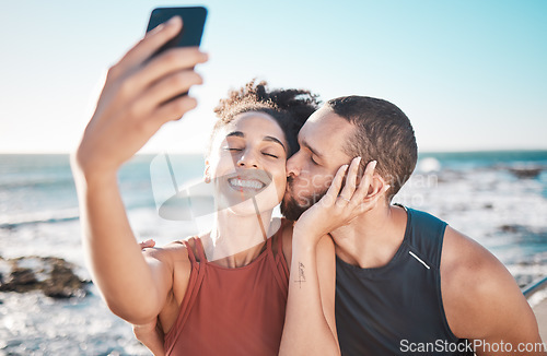 Image of Selfie kiss, gratitude and couple with a phone for streaming, training and love at the beach in Bali. Caring, exercise and affectionate man and woman with a smile for a mobile photo after a workout