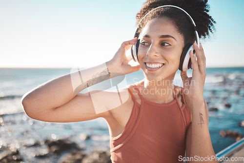 Image of Music, thinking and fitness with a sports black woman by the sea during her running workout at the sea. Exercise, training and radio with a female runner listening to audio by the ocean in summer