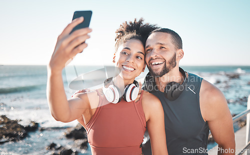 Image of Fitness, couple and phone for selfie at the beach with smile for running, exercise or workout together. Happy woman and man smiling in happiness looking at smartphone for photo after run by the ocean