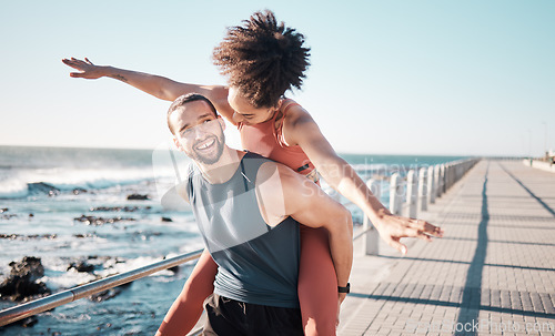 Image of Summer, freedom and couple piggyback by ocean enjoying holiday, vacation and quality time on weekend. Love, dating and black man and woman relax after running, fitness workout and training by beach