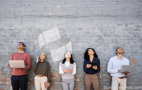 Image of Diversity, technology and team standing at wall looking up and working at tech development company waiting for hr. Human resources, job opportunity and group of people with laptop, phone and tablet.