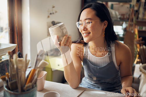 Image of Artist, Asian and woman as small business entrepreneur happy about design and product at a workshop. Pottery, mug and clay sculpture by creative startup female smiling and satisfied by art