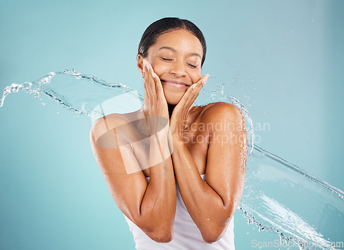 Image of Water, splash and woman in a studio for a skincare, beauty and natural cosmetic face routine. Health, wellness and female model with a fresh organic facial treatment isolated by a blue background.