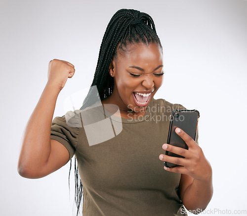 Image of Black woman, phone and victory for winning, discount or sale against a grey studio background. Happy African American female winner excited for achievement, good news or celebrating win on smartphone