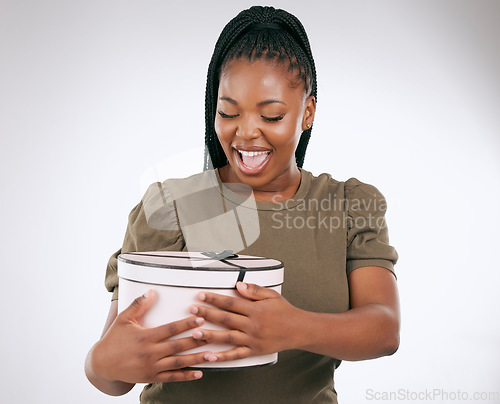 Image of Gift, box and black woman on studio background, present or smile. Happy female, package and surprise with ribbon for birthday, excited celebration and wow product of promotion, happiness and giveaway