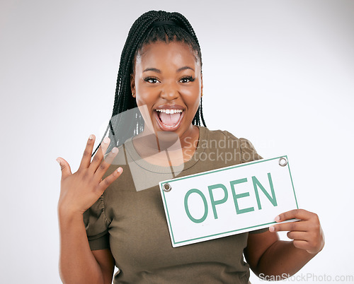 Image of Black woman, excited and holding open sign for announcement or message against a grey studio background. Portrait of African American female manager advertising startup opening or ready for service