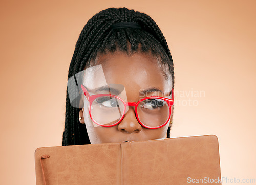 Image of Black woman, notebook and hide face in studio for thinking, glasses or planning schedule for small business online. Young african entrepreneur, book or ideas for goal, vision or notes by background