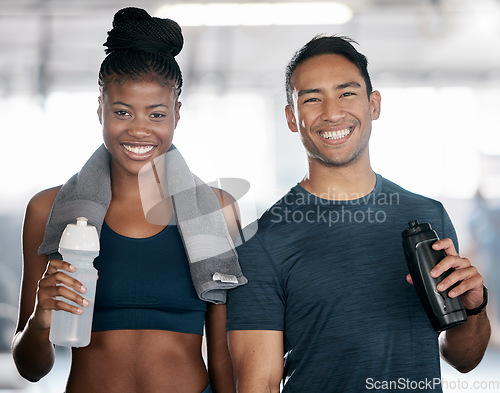 Image of Portrait, fitness and drinking water with a sports couple in the gym together after a workout. Diversity, smile and towel with a happy young man and woman in a health center for exercise or training