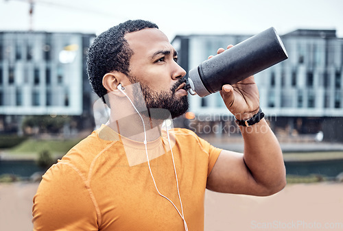 Image of Fitness, athlete and man drinking water in the city after running for exercise or marathon training. Sports, hydration and male runner enjoying a drink after a intense cardio sport workout in town.