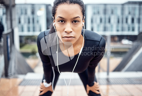 Image of Portrait, tired and serious with a sports black woman taking a rest from her exercise workout in the city. Face, music and fitness with a young female runner or athlete training alone outside