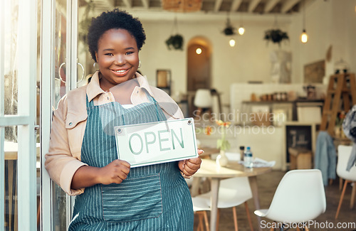 Image of Open sign, portrait and black woman business startup in cafe, restaurant or retail store with smile for success. Boss, manager or person hand holding board for welcome service at new coffee shop