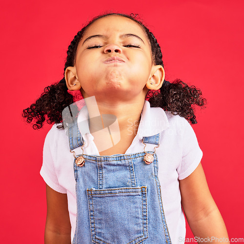 Image of Attitude, childhood and face of girl on red background in studio with angry, upset and frustrated reaction. Emoji, comic and young kid with air in cheeks, tantrum behaviour and mad facial expression