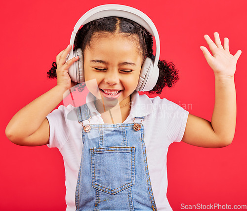 Image of Dancing, child and headphones for music, fun radio and girls podcast on isolated red background and studio. Smile, happy and energy kid listening to dance audio, sound and streaming media on backdrop