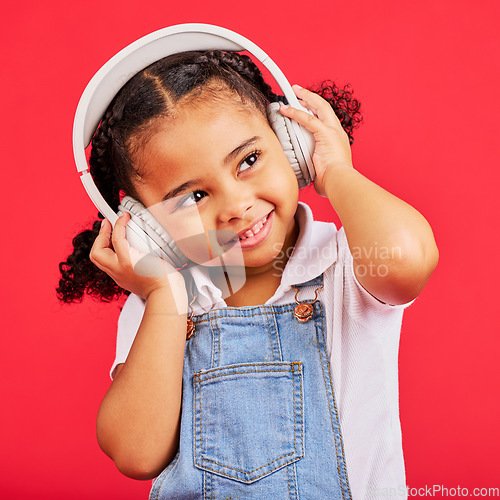 Image of Happy, kid and headphones for music, radio and fun podcast on isolated red background and dancing studio. Smile, little girl and child listening to dance audio, sound and streaming media on backdrop