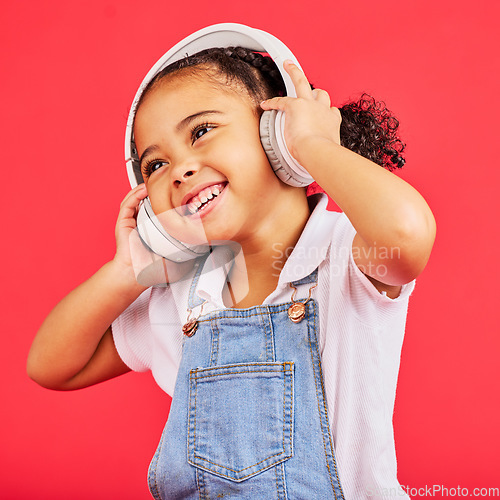 Image of Dancing, kid and headphones for music, fun radio and girls podcast on isolated red background and studio. Smile, happy and energy child listening to dance audio, sound and streaming media on backdrop