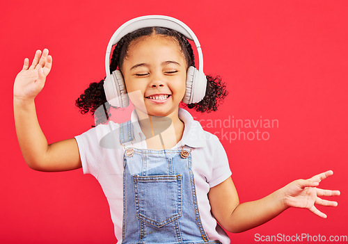 Image of Dancing, energy and child on music headphones, fun radio or loud podcast on isolated red background or studio backdrop. Smile, happy kid and girl listening to dance audio, sound and streaming media