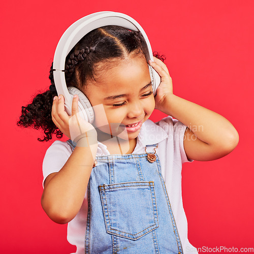 Image of Happy, child and headphones for music, radio and fun podcast on isolated red background and dancing studio. Smile, little girl and kid listening to dance audio, song and streaming media on backdrop