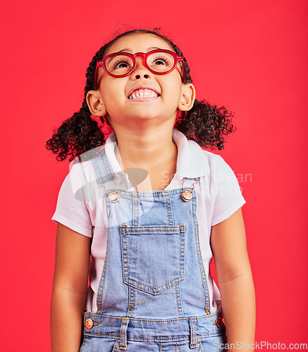 Image of Looking up, child and fashion glasses on red background in kids style, eyes care and wellness health insurance. Smile, happy and little girl with optometry frames, vision support or retail sales deal