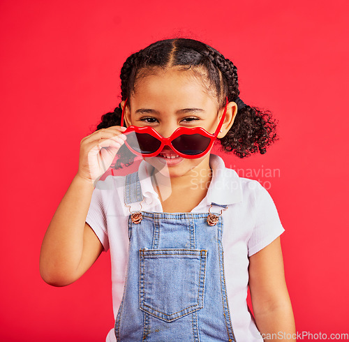 Image of Child portrait, fashion and glasses on isolated red background in summer trend, holiday style and cool vacation. Smile, happy and kid with sunglasses for eyes healthcare, wellness and sun protection