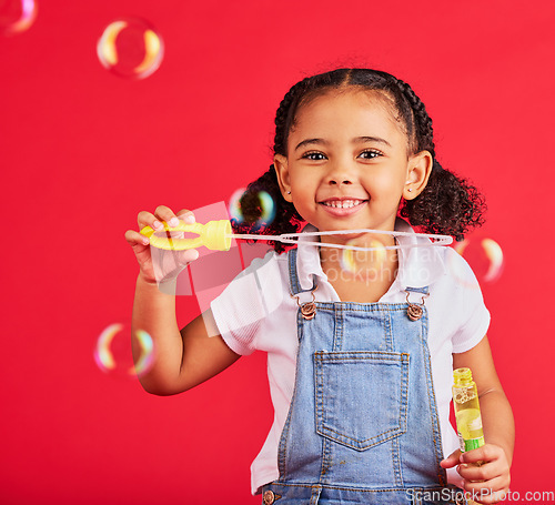 Image of Little girl, portrait or bubbles playing on isolated red background in hand eye coordination, kids activity or fun game. Smile, happy or child and soap wand, studio toy or breathing development skill