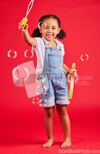 Image of Child, portrait or bubbles playing on isolated red background in hand eye coordination, kids activity or fun game. Smile, happy or little girl and soap wand, studio toy or breathing development skill