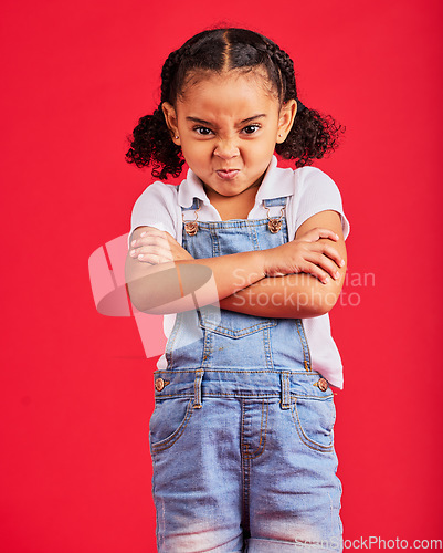 Image of Child, arms crossed or angry portrait on isolated red background for tantrum face, behavior problem or stubborn. Mad, annoyed or frustrated little girl with sulking, grumpy or anger facial expression