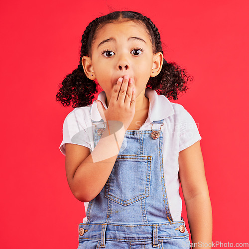 Image of Shocked kid, portrait and hand on mouth in secret, oops and mistake facial expression on isolated red background. Child, little girl and surprised face in gossip, news or emoji at studio announcement