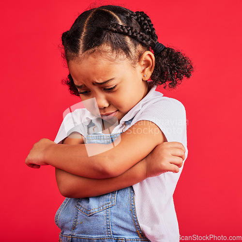 Image of Kid, arms crossed or crying expression on isolated red background in depression, mental health or burnout. Upset, unhappy or little girl with sad, sulking or grumpy face in bullying crisis or anxiety