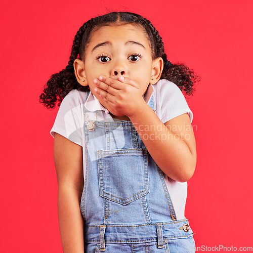 Image of Shocked child, portrait and hand on mouth in secret, oops and mistake facial expression on isolated red background. Kid, little girl and surprised face in gossip, news or emoji at studio announcement