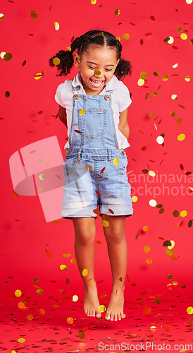 Image of Young girl, kid jump with confetti, happiness and party with celebration, gold and glitter isolated against red background. Fun, youth and happy child at event, celebrate and birthday in studio