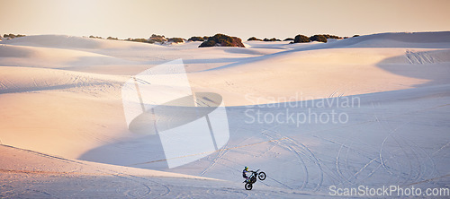 Image of Desert, motorcycle and athlete doing a sport jump for outdoor competition, training or exercise. Extreme sports, sand dunes and man riding motorbike doing skill, trick or challenge for race in Dubai.
