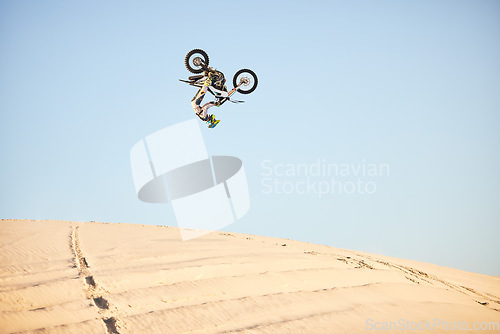 Image of Motorcycle, jump and sports athlete in desert, dirt bike rally outdoor with extreme sport stunt, power and action. Nature, adventure and freedom, fitness challenge and biker person, mockup and travel