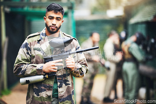 Image of Paintball game and portrait of a man with gun and safety uniform for outdoor shooting battle. Assertive and young indian guy in camouflage clothing ready for shooter sport and activity.