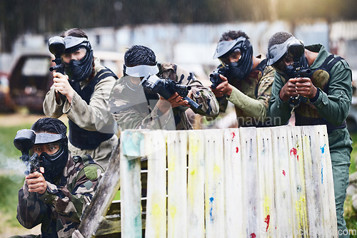 Image of Paintball, gun or team play in a shooting game together on a fun battlefield on holiday. Men on a mission, fitness or players aim with military weapons gear for survival in an outdoor competition