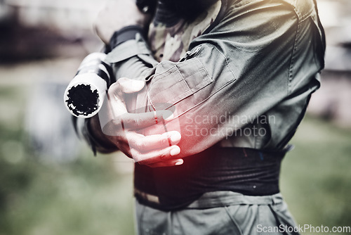 Image of Paintball, pain or man with an elbow injury after playing a shooting game on a fun battlefield on holiday. Red glow, fitness or hands of player in an arm accident in an outdoor military competition