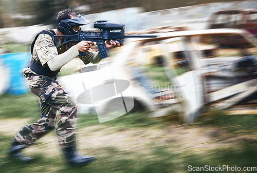 Image of Paintball, aim and man with a gun for a game with blur motion at an outdoor arena or field. Challenge, competition and male soldier with a camouflage military outfit shooting a rifle on a battlefield