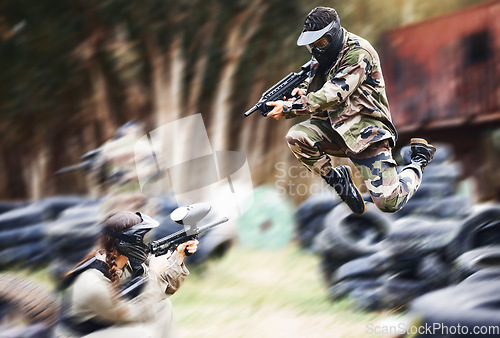 Image of Paintball, gun or people play in a shooting game with fast action on a fun battlefield on holiday. Man on mission, fitness or player jumping with weapons gear for survival in an outdoor competition