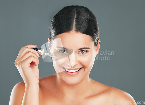 Image of Woman, beauty portrait and facial dropper, essential oil and aesthetic makeup on studio background. Happy model face, liquid cosmetics and hyaluronic acid product of serum, body and transformation