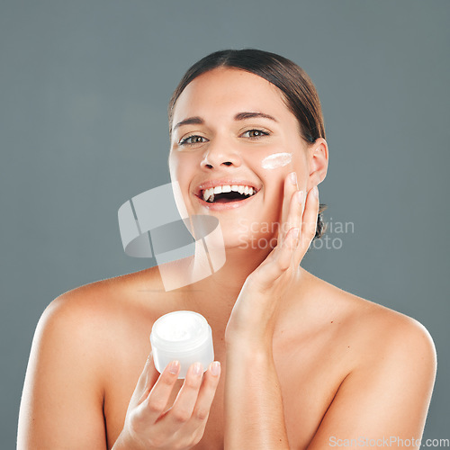 Image of Woman apply cream for face, happy in portrait and beauty, skincare and moisturizer isolated on studio background. Sunscreen, lotion and healthy skin with glow, cosmetics and facial treatment product