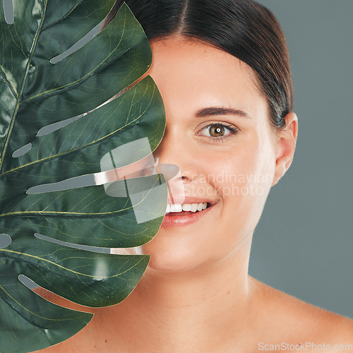 Image of Palm leaf, face and woman in portrait with smile, beauty and skincare with natural cosmetics isolated in studio background. Healthy skin, wellness and glow, facial and eco friendly cosmetic treatment