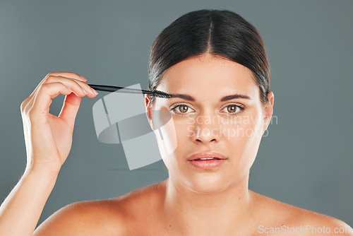 Image of Eyebrow skincare, brush and portrait of woman in studio for headshot, beauty transformation and cosmetics. Face, makeup and brushing brows with facial tool, model and hair on eyes for clean aesthetic