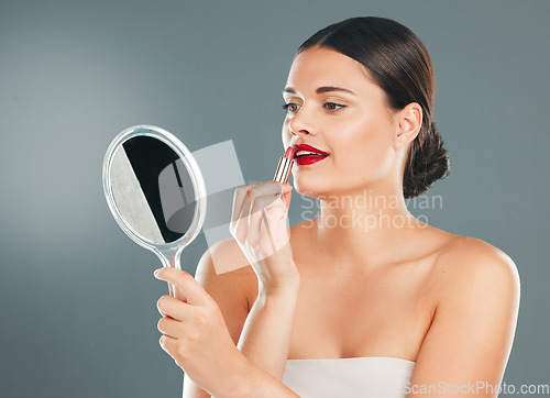 Image of Lipstick, woman and mirror on studio background for beauty, fashion and aesthetics. Young model, red lips and makeup application with reflection for glamour cosmetics, elegant skincare or cosmetology