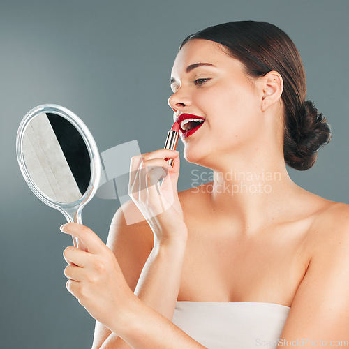 Image of Red lipstick, mirror and woman face with smile happy with cosmetics and makeup brush. Mouth, female and beauty model looking at reflection with cosmetic tool with studio background and lips product