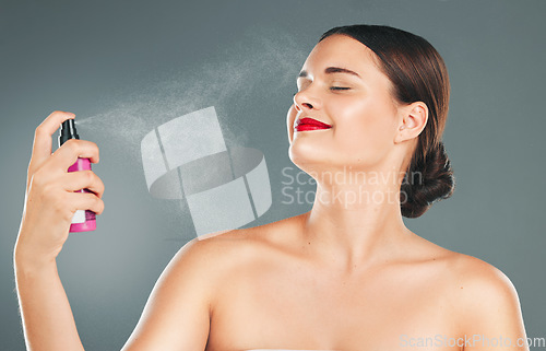 Image of Cosmetic, face spray and woman in a studio for a makeup, skincare and natural facial routine. Self care, wellness and female model with a facial cosmetics treatment isolated by a gray background.