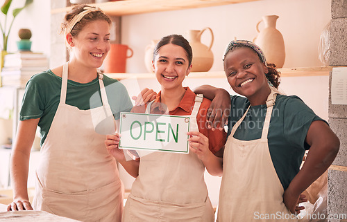 Image of Small business, partnership and women with open sign for pottery startup, creative workshop and art studio. Smile, teamwork and owners happy for welcome to ceramics, clay sculpture and artwork store